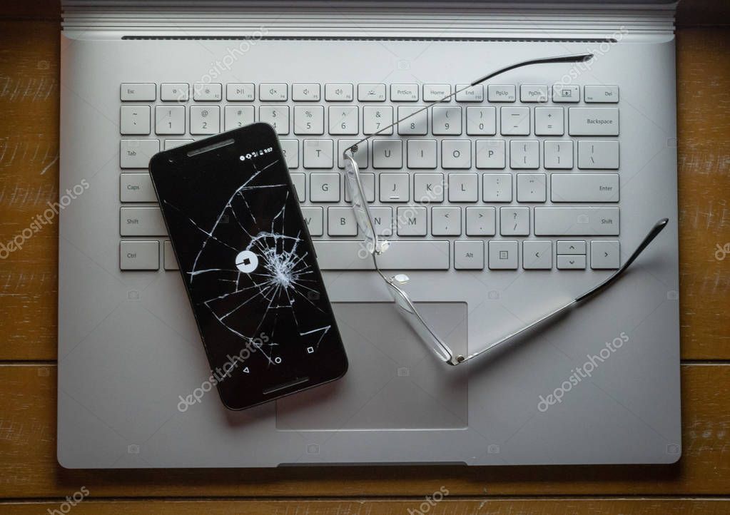 SAN FRANCISCO, CA  APRIL 8, 2018: Snapchat, disappear message social media app, logo on a broken cell phone sitting on a laptop next to glasses.