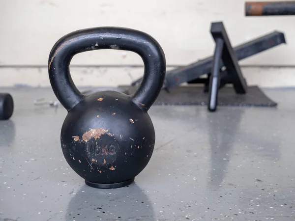 Negro, 10 kg kettlebell sentado en el suelo del gimnasio duro — Foto de Stock