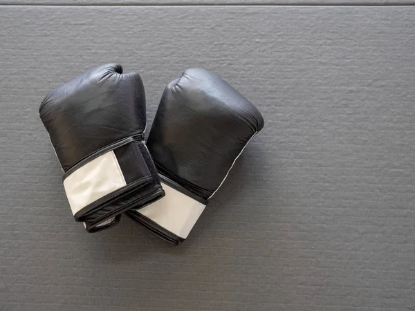 Alta vista de guantes de boxeo negros sentados sobre esteras grises de boxeo — Foto de Stock