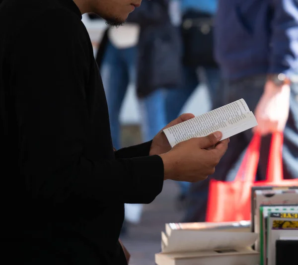 Hombre de pie e intensamente leyendo un libro de bolsillo — Foto de Stock