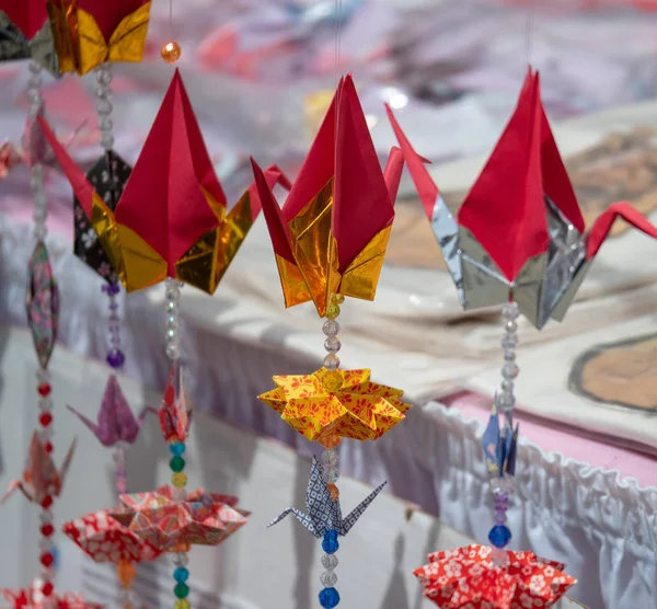 Figuras de origami en grúa suspendida decorando un mercado al aire libre — Foto de Stock
