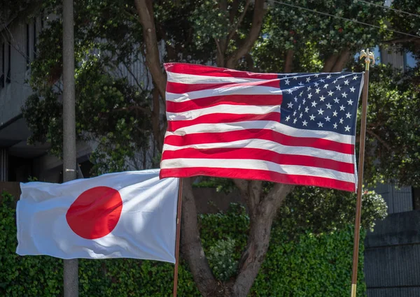 Banderas japonesas y estadounidenses que fluyen en el viento en poder de los abanderados — Foto de Stock