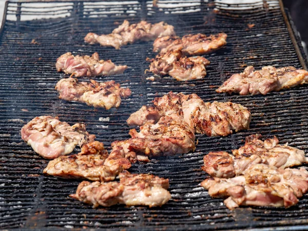 Slabs of pork cooking on grill at a barbeque