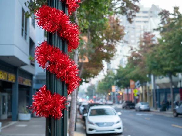Polo de luz en el área de la ciudad envuelto con cinta decorativa roja en la temporada navideña — Foto de Stock