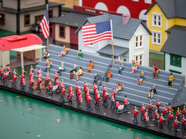 รูปปั้นขนาดเล็กวงดนตรีเดินขบวนในขบวนพาเหรดกับผู้มองที่มีธงสหรัฐอเมริกา — ภาพถ่ายสต็อก