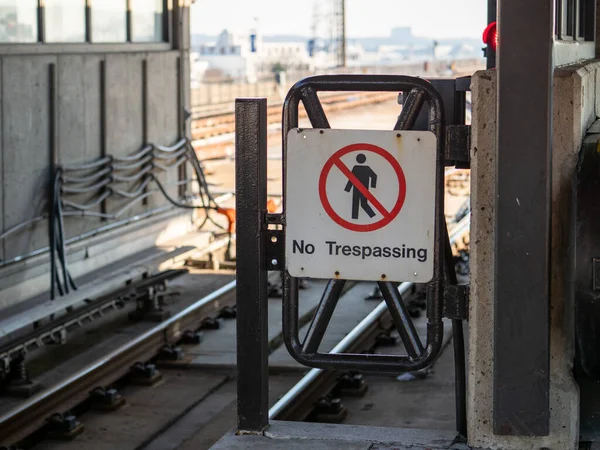 No trespassing sign with crossed out walker leading to subway train tracks