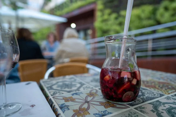Pitcher of red sangria with fruit on table at outdoor restaurant