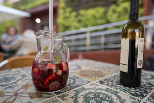 Pitcher of red sangria sitting next to red wine bottle on table at restaurant