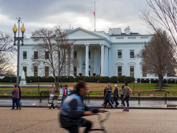 Hombre en bicicleta carreras más allá de la Casa Blanca césped en día nublado — Foto de Stock