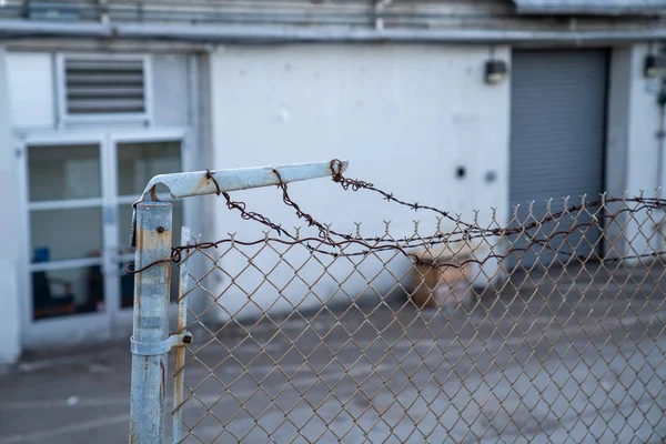 Arame farpado enferrujado em cerca quebrada na frente do armazém — Fotografia de Stock