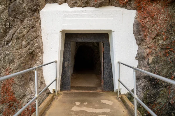 Betonggångväg som leder in i mörk tunnel in i bergssidan — Stockfoto
