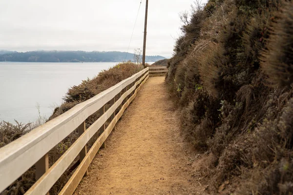 Camino de la suciedad con carril blanco con vistas al acantilado un cuerpo de agua — Foto de Stock