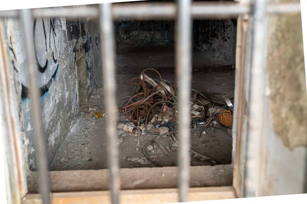 Varios desechos y basura a través de una puerta de acero en una ventana en el complejo de edificios abandonados — Foto de Stock