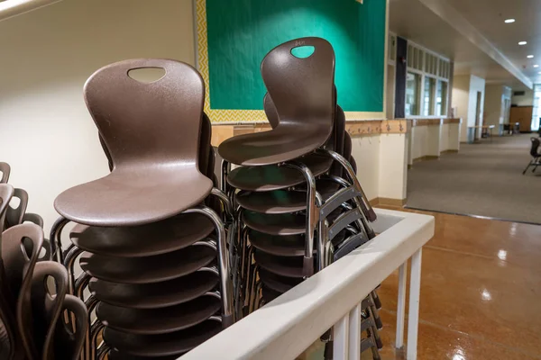 Dos filas de sillas de apilamiento marrón en un entorno escolar apiladas bajo las escaleras — Foto de Stock
