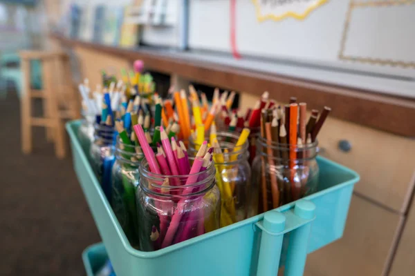 Sınıfta sanat eserleri için kavanozlar dolusu renkli kalemlerle dolu bir araba.