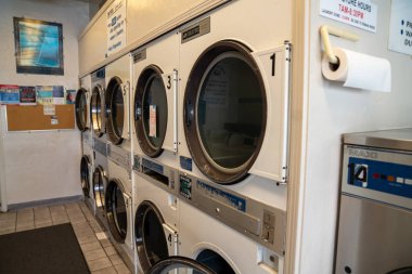 Çamaşırhanede sıra sıra çamaşır ve kurutma makineleri.