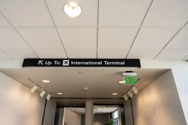 Hasta la señal de terminal internacional que apunta a la parte superior izquierda colgando en el techo en el aeropuerto — Foto de Stock
