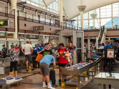 Travelers collect belongings after passing security checkpoint at Denver International Airport clipart