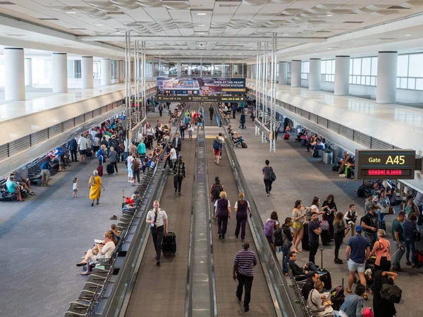 Piloten, werknemers en passagiers in een drukke luchthaventerminal met bewegende loopbruggen — Stockfoto