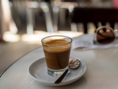Expresso coffee in small glass with spoon on white table in restaurant