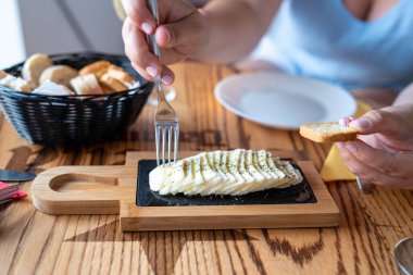 Woman s hands picking cheese board with bread at restaurant table