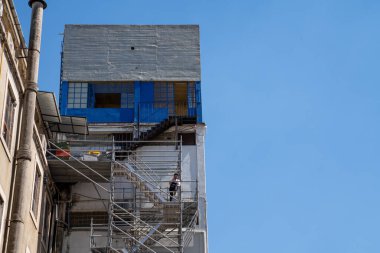 Adam inşaat halindeki bir deponun dışında cep telefonuyla konuşuyor.