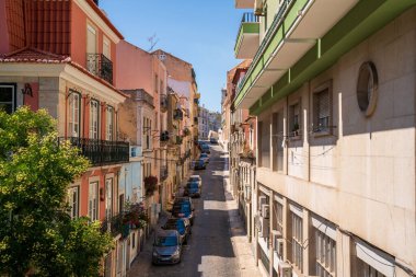 Şehirdeki çeşitli ticari ve konut binaları arasında park etmiş çeşitli arabaların olduğu ara sokaklar.