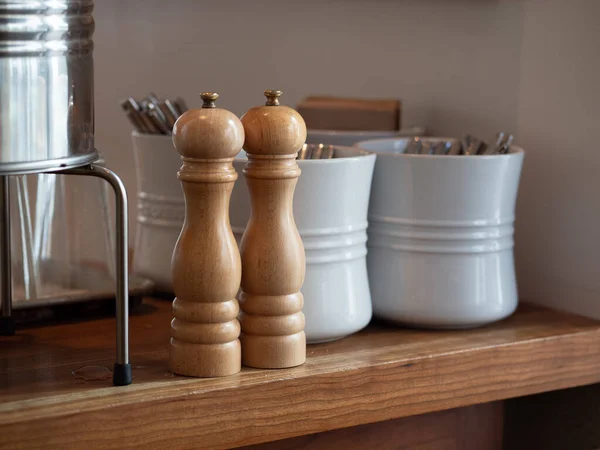 Деревянная ручная рукоятка соль и перцовый шейкер на столе с посудой в керамических горшках — стоковое фото