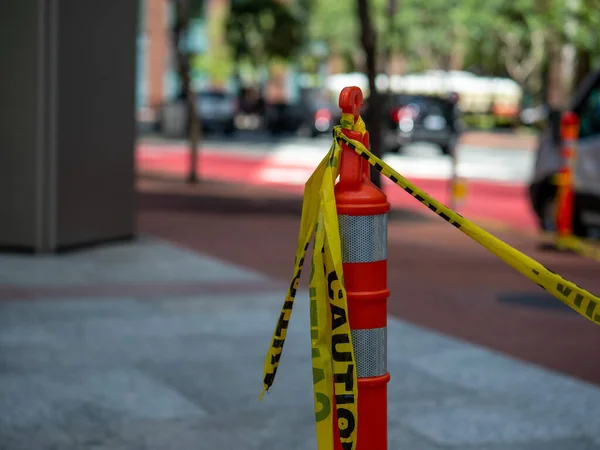 Cinta amarilla de precaución atada al cono de seguridad naranja colocado en la calle — Foto de Stock