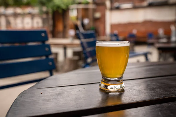 Gyllene öl i litet smakglas på bord på uteservering — Stockfoto