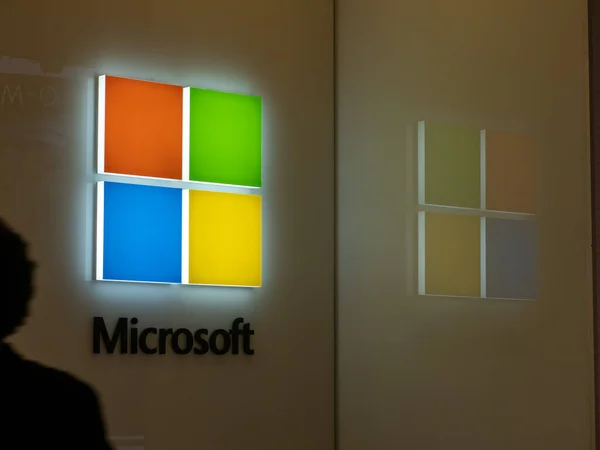 Logotipo de Microsoft y reflexionar con el hombre caminando en la sombra — Foto de Stock