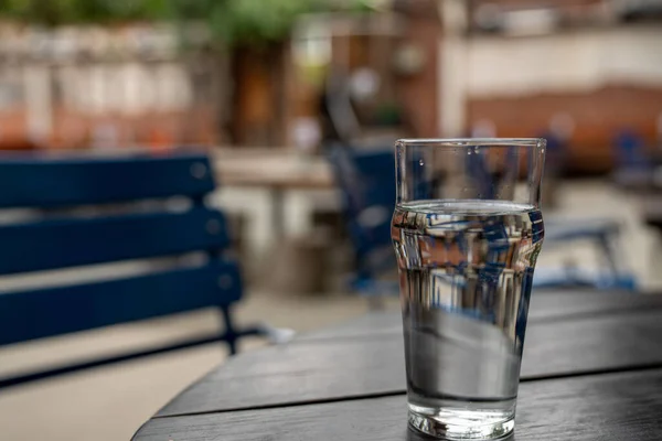 Un vaso lleno de agua sentado en una mesa de picnic de madera en el restaurante Imagen De Stock