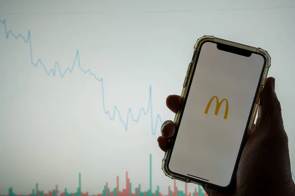 McDonald s mobile app logo on iPhone in front of white stock market chart with graph going down in value — Stock Photo, Image