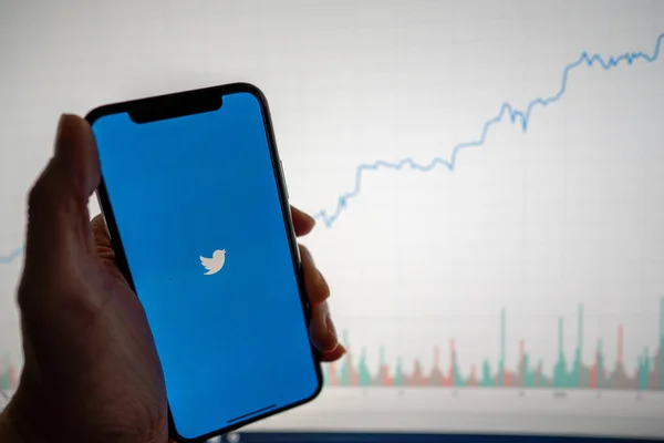 Aplicación de Twitter y logotipo en el teléfono con el gráfico de acciones financieras blancas con un aumento de precios positivo en segundo plano Fotos De Stock