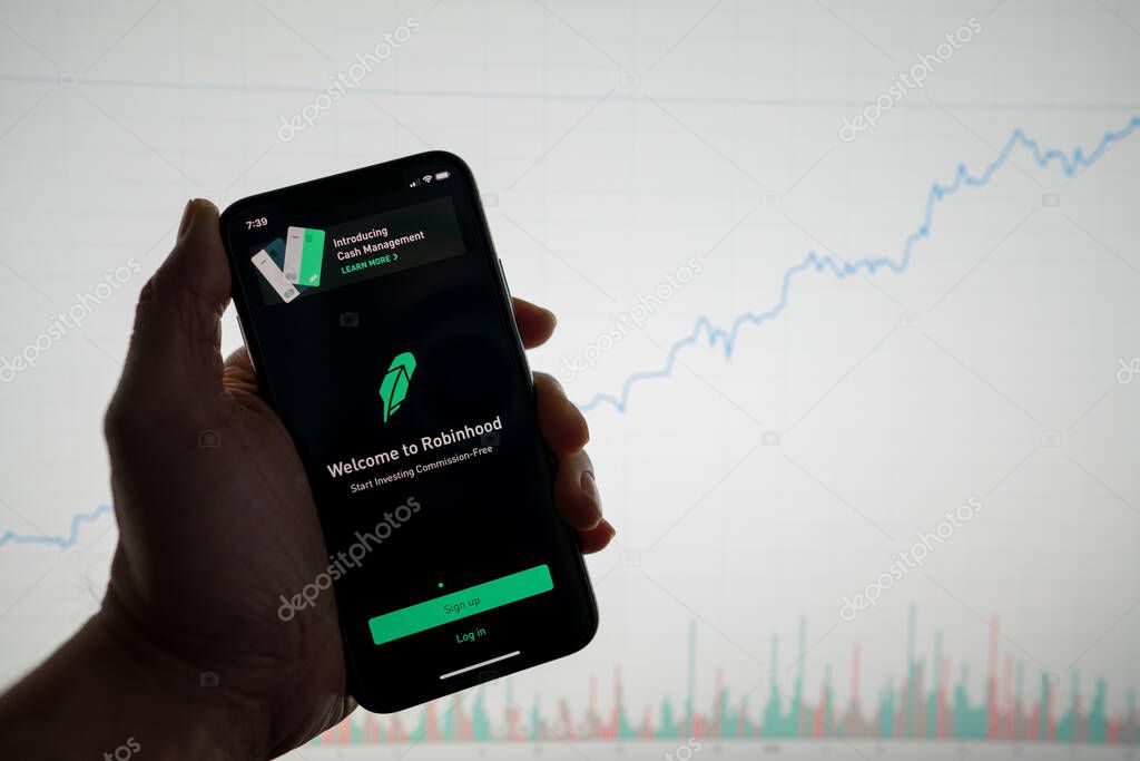 Robinhood app on phone with white financial stock chart with price rising upward positive in background