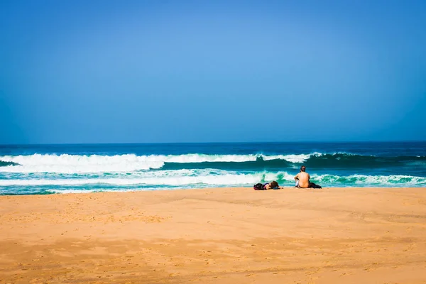 Junges Paar sitzt zusammen auf einem Sand am Meer — Stockfoto