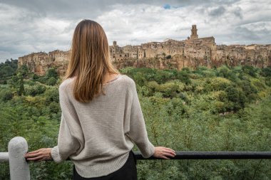 Woman looking on medieval village Pitigliano, Italy clipart
