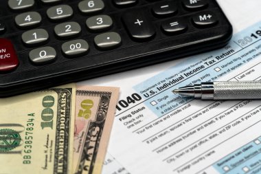 Hesap makinesi, kalem ve dolar banknotlu 1040 vergi formu. finans kavramı.