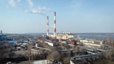 Güneş 'in aksine fabrika borusundan büyük, kırmızı ve beyaz bir boruyla sanayi bölgesi dökülüyor. Çevrenin kirliliği: dumanlı bir pipo. Hava görünümü