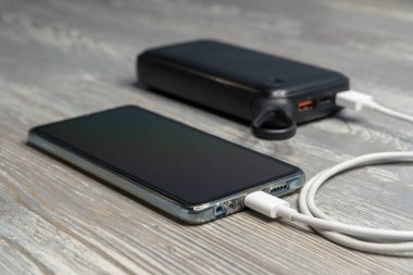 Telefon ve şarj cihazları, güç depolama ve elektrik kablosu, ahşap arka planda