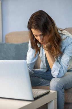 Ev ofisindeki kanepede oturan kadın. Evden çalışan bir dizüstü bilgisayar.