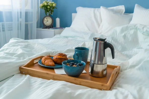 Breakfast served in bed on wooden tray with coffee and croissants. Good morning