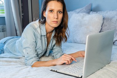 Kadın ya da akıllı telefon ve dizüstü bilgisayarda uzaktan internet işi yapan başarılı bir öğrenci, üniversite kütüphanesinde teknoloji kullanırken oturan bir kız öğrenci.