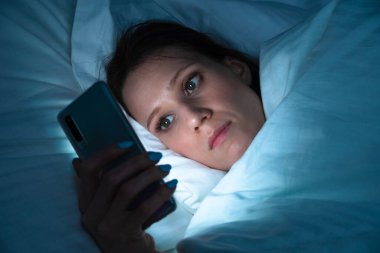 Uykudan önce uygulamaları kontrol etmek - kadın gece uyurken akıllı telefon kullanır