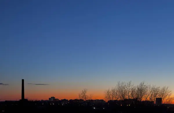 夕暮れの空と木と工業用管内町の地平線 — ストック写真