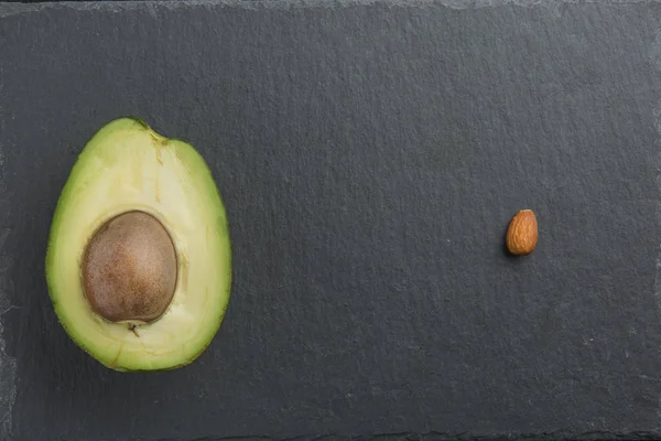 Нарезанный авокадо с миндалем на темном фоне — стоковое фото