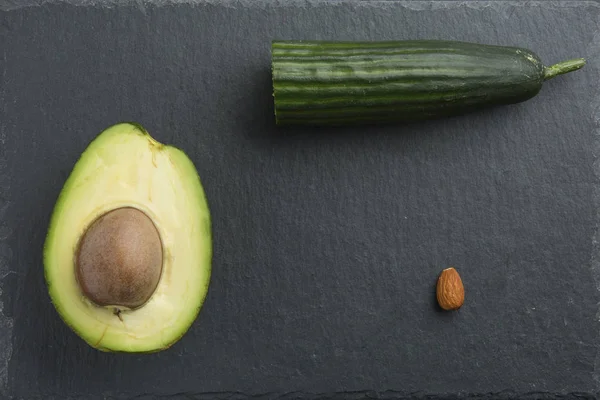 Нарезанный авокадо с миндалем и огурцом на темном фоне — стоковое фото