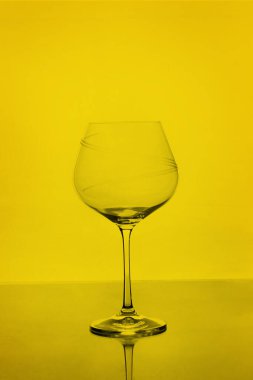 Sarı arkaplanda izole edilmiş boş şarap kadehini temizle