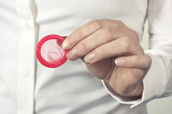 Red condom in hand for safe sex. — Stock Photo, Image