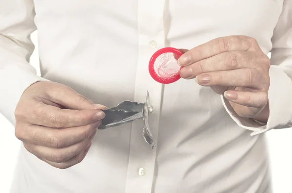 Vrouwelijke handen openen een nieuw condoom. — Stockfoto